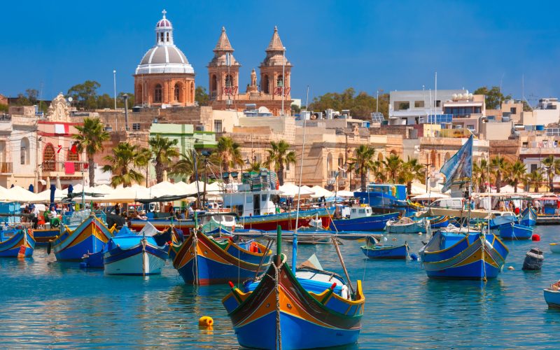 Traditional eyed colorful boats Luzzu in the Harbor of Mediterranean fishing village Marsaxlokk, Malta